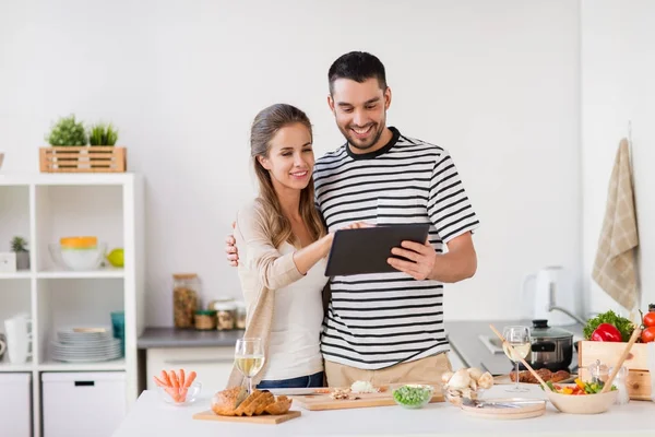 Šťastný pár s počítačem tablet pc, vaření jídlo doma — Stock fotografie