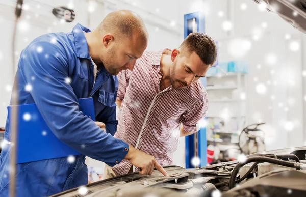 Automechaniker mit Klemmbrett und Mann im Autohaus — Stockfoto