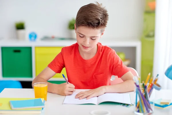Ευτυχισμένος φοιτητής αγόρι γράφοντας στο τετράδιο στο σπίτι — Φωτογραφία Αρχείου