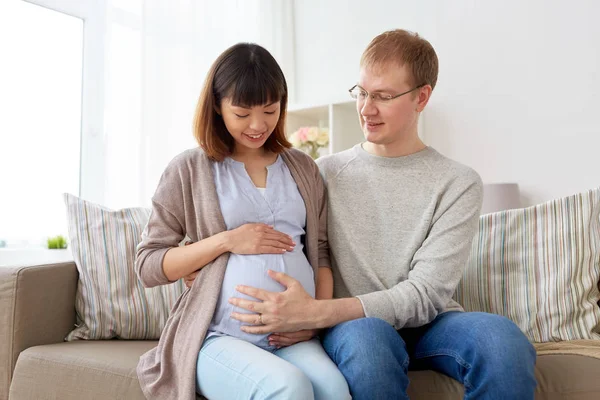 Счастливая беременная жена с мужем дома — стоковое фото