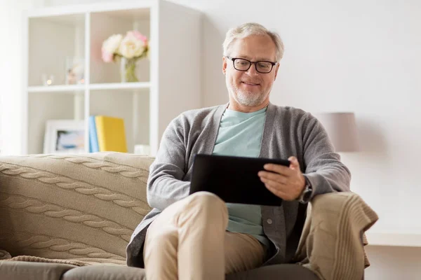 Senior man met tablet pc zittend op de Bank thuis — Stockfoto