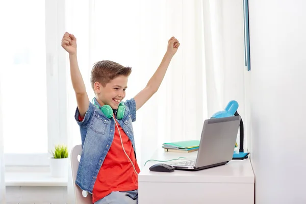 Boy with headphones playing video game on laptop Stock Photo