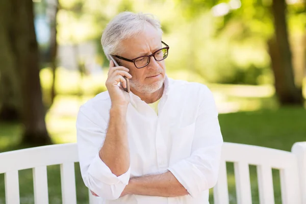 Hombre mayor llamando en el teléfono inteligente en el parque de verano — Foto de Stock