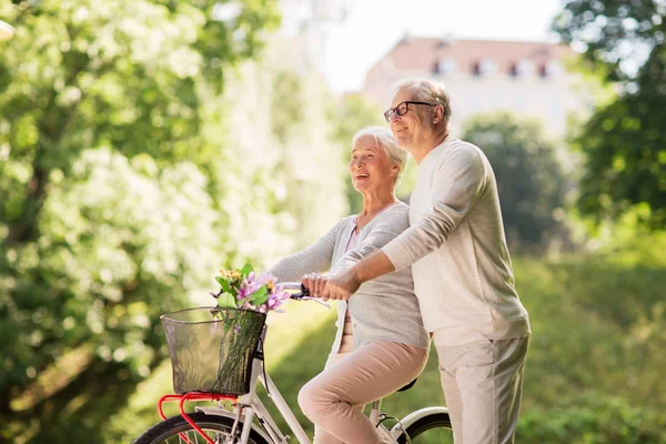 Счастливая пожилая пара с велосипедом в летнем парке — стоковое фото