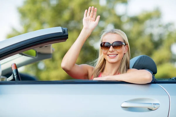 Gelukkig jonge vrouw in converteerbare auto zwaaien hand — Stockfoto