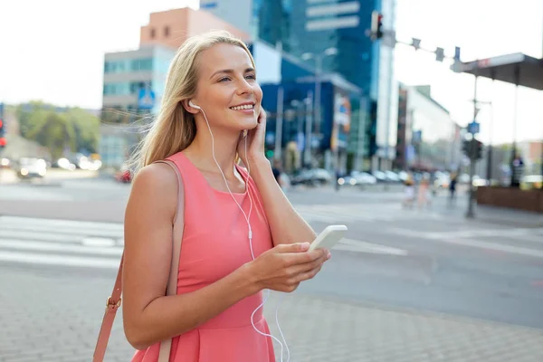 Šťastná mladá žena s smartphone a sluchátka — Stock fotografie