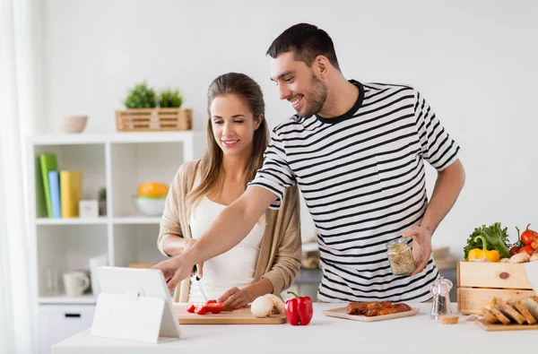 Šťastný pár s počítačem tablet pc, vaření jídlo doma — Stock fotografie