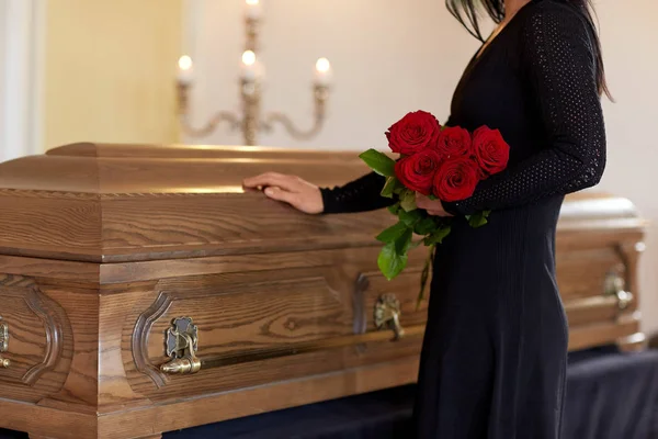 Mulher triste com rosas vermelhas e caixão no funeral — Fotografia de Stock