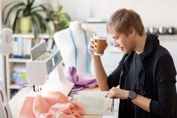 Σχεδιαστής μόδας με καφέ και βιβλίο στο studio — Φωτογραφία Αρχείου