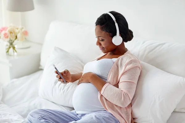 Femme enceinte dans un casque avec smartphone — Photo