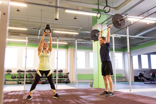 Uomo e donna con pesi che esercitano in palestra — Foto Stock