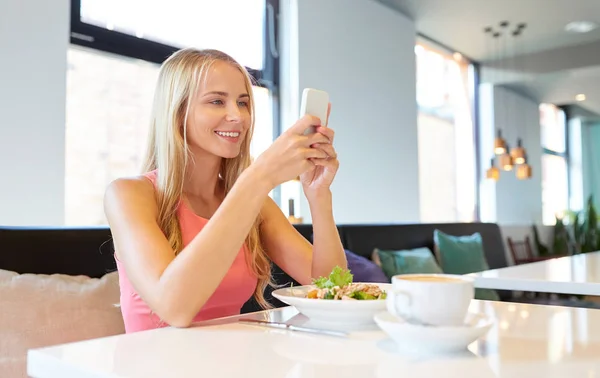 Happy woman with smartphone eating at restaurant — Stock Photo, Image