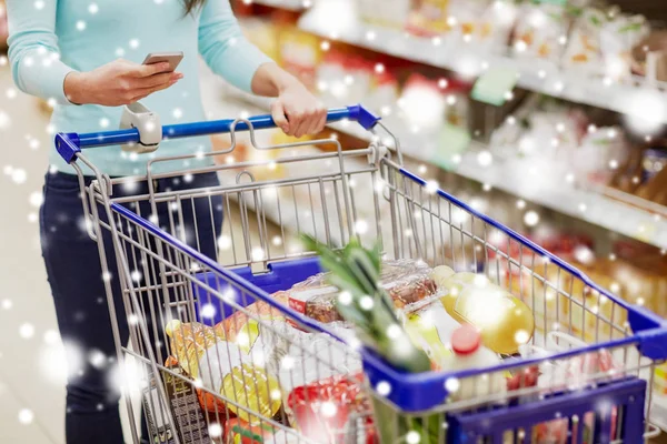 Klant met voedsel in winkelwagen bij supermarkt — Stockfoto