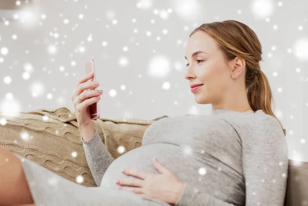 Mujer embarazada feliz con teléfono inteligente en casa — Foto de Stock