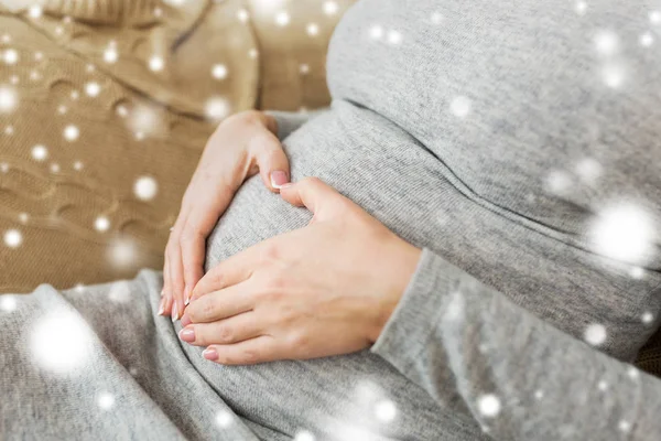 Zwangere vrouw maken hart gebaar op haar buik — Stockfoto