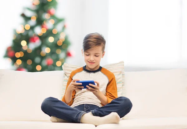 Мальчик играет на смартфоне дома на Рождество — стоковое фото