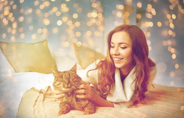 Feliz joven con gato acostado en la cama en casa —  Fotos de Stock