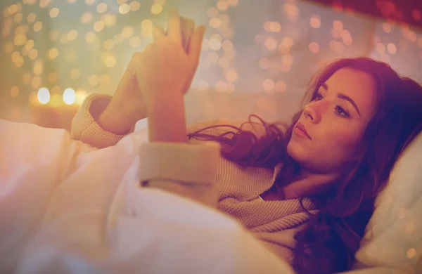 Mujer joven con teléfono inteligente en la cama en el dormitorio en casa — Foto de Stock