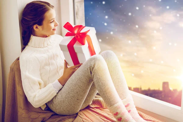 Chica con regalo de Navidad en el alféizar de la ventana en invierno —  Fotos de Stock