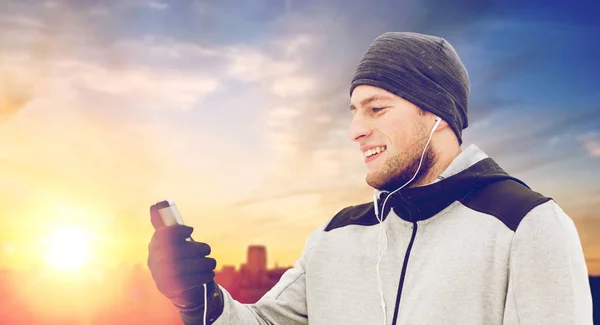 Homem feliz com fones de ouvido e smartphone no inverno — Fotografia de Stock