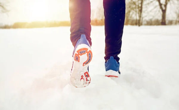 Närbild av fötter som löper längs snöig vinterväg — Stockfoto