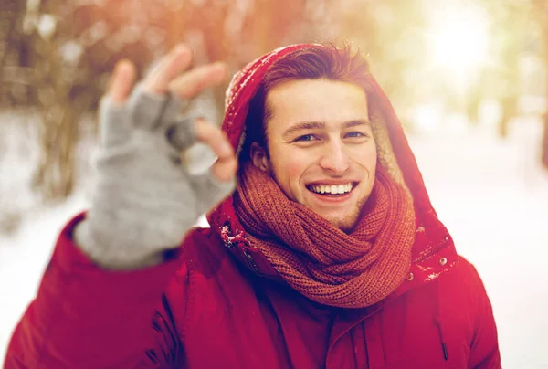 Šťastný muž v zimní bundě ukazující značka ok ruky — Stock fotografie