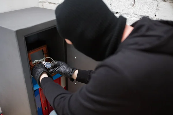 Ladrón robando objetos de valor de caja fuerte en la escena del crimen — Foto de Stock