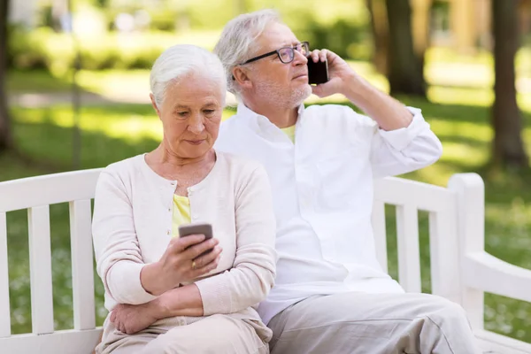 Glückliches Seniorenpaar mit Smartphones im Park — Stockfoto