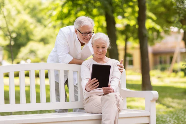 Gelukkige senior paar met de tablet pc in zomer park — Stockfoto