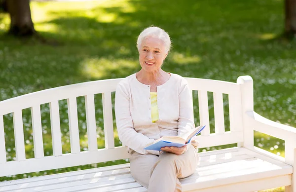 Mulher sênior feliz livro de leitura no parque de verão — Fotografia de Stock