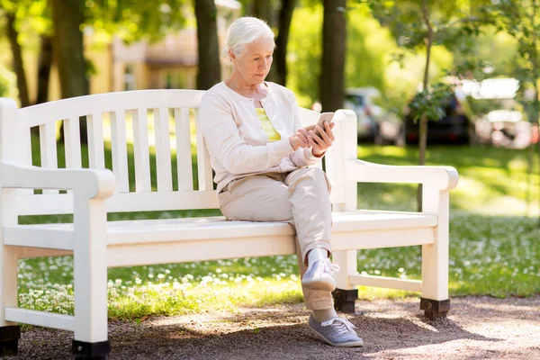 Donna anziana con smartphone al parco estivo — Foto Stock