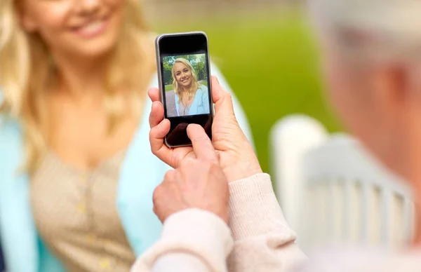 Старшая мать фотографирует дочь по смартфону — стоковое фото