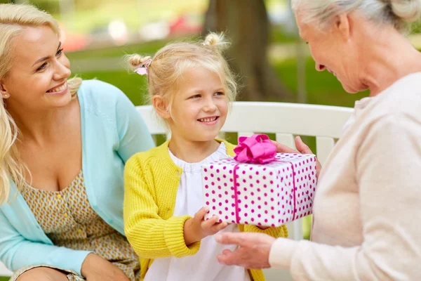 Feliz familia dando regalo a la abuela en el parque — Foto de Stock