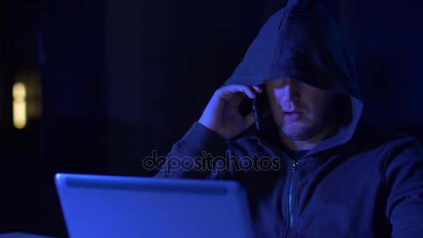 Хакер с ноутбуком звонит на мобильный телефон — стоковое видео