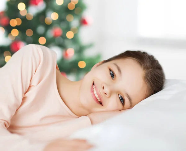 Heureuse fille souriante couchée éveillée au lit à Noël — Photo