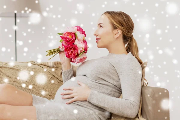 Glad gravid kvinna med blommor hemma — Stockfoto