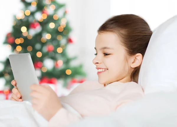 Счастливая девушка в постели с планшетным компьютером в руках — стоковое фото