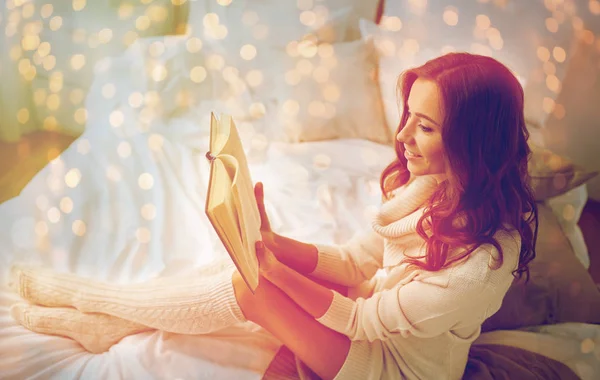 Щаслива молода жінка читає книгу в ліжку вдома — стокове фото