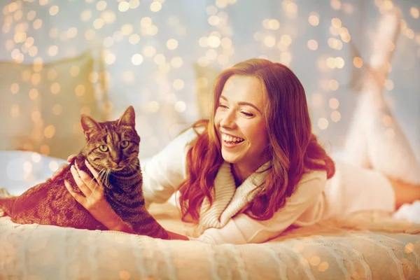 Ευτυχισμένη γυναίκα με γάτα ξαπλωμένη στο κρεβάτι στο σπίτι — Φωτογραφία Αρχείου