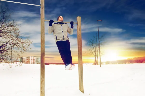 Mladý muž cvičení na hrazdě v zimě — Stock fotografie