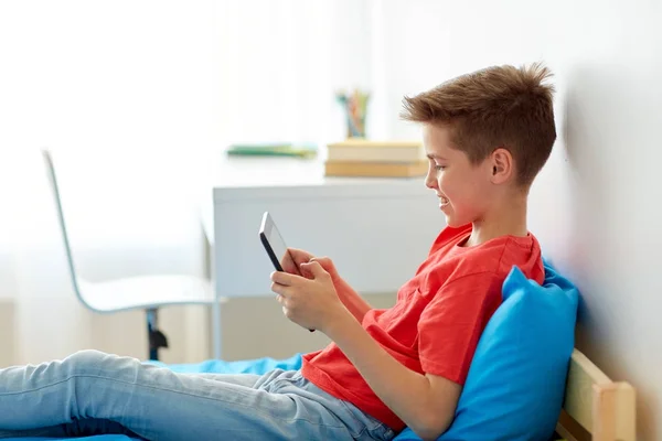 Улыбающийся мальчик с планшетным компьютером дома — стоковое фото