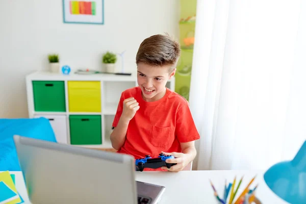 Pojke med gamepad spelar videospel på laptop — Stockfoto