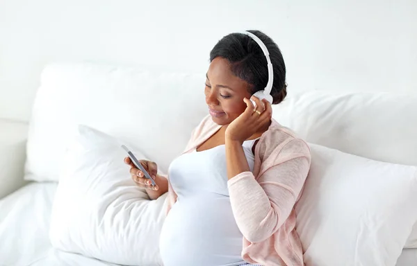 Femme enceinte dans un casque avec smartphone — Photo