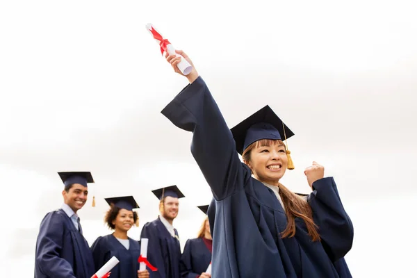 Šťastní studenti v minometných tabulích s diplomy — Stock fotografie