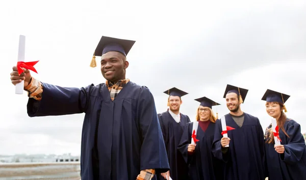 Studenti felici in mortai con diplomi — Foto Stock