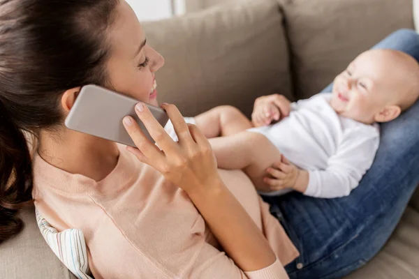 Mother with baby calling on smartphone at home — Stock Photo, Image