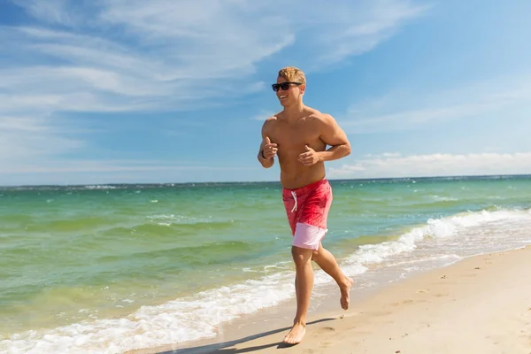 夏のビーチに沿って実行している幸せな男 ロイヤリティフリーのストック画像