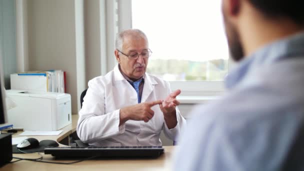 Старший лікар розмовляє з пацієнтом чоловічої статі в лікарні — стокове відео