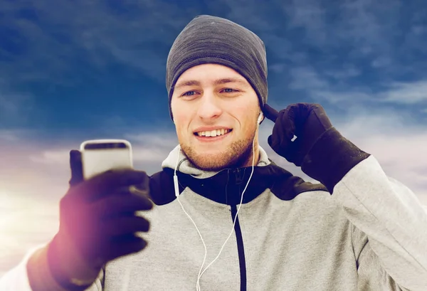 冬のスマート フォンのイヤホンと幸せな男 — ストック写真