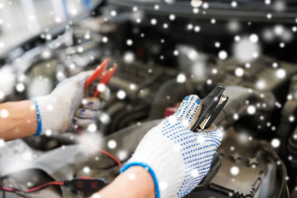 Auto mechanic hands with cleats charging battery — Stock Photo, Image